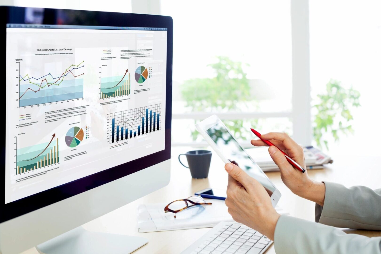 Person analyzing graphs on computer and tablet.